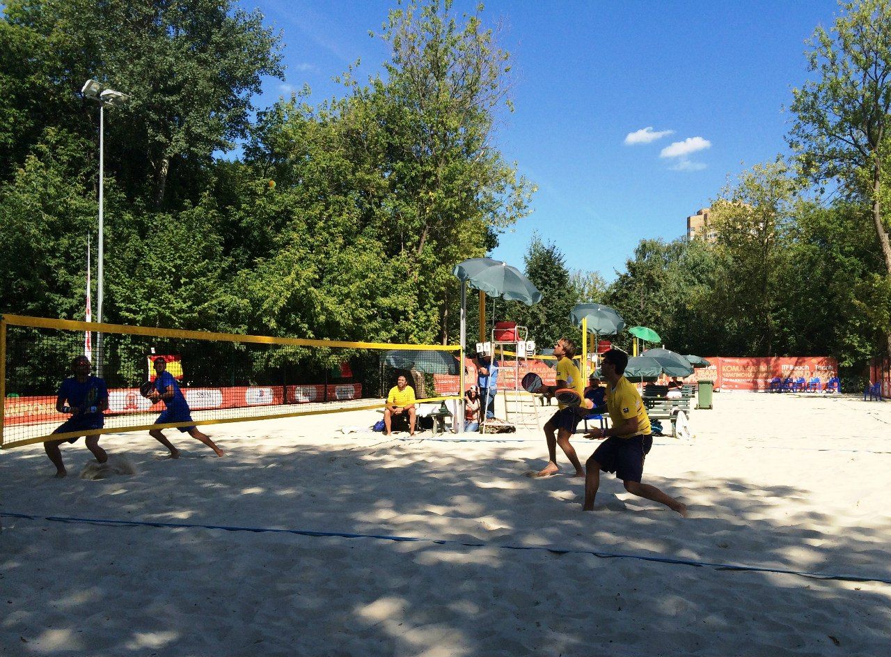 Partida de beach tennis em dupla numa quadra de areia