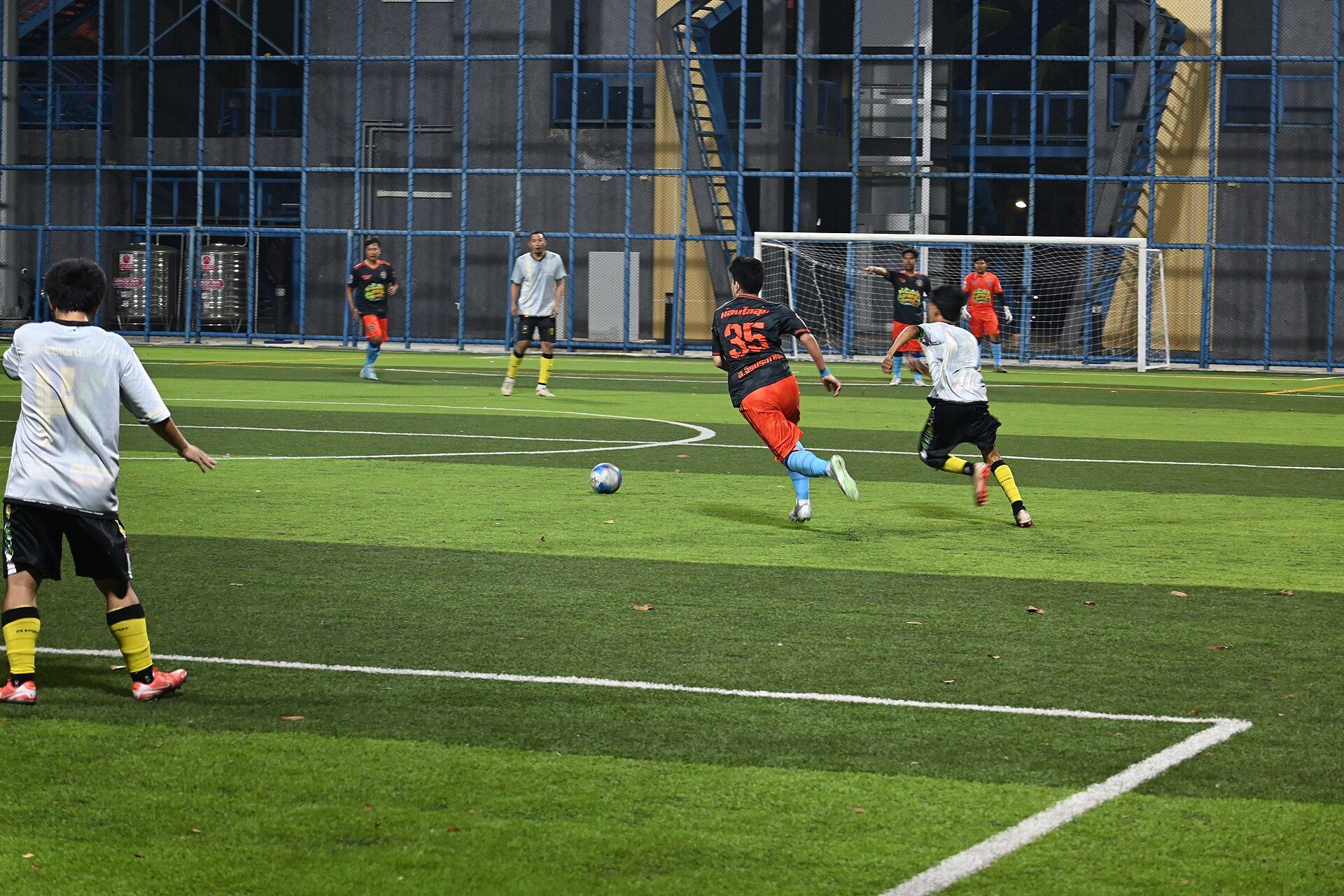Jogo de futebol à noite em campo sintético sob refletores